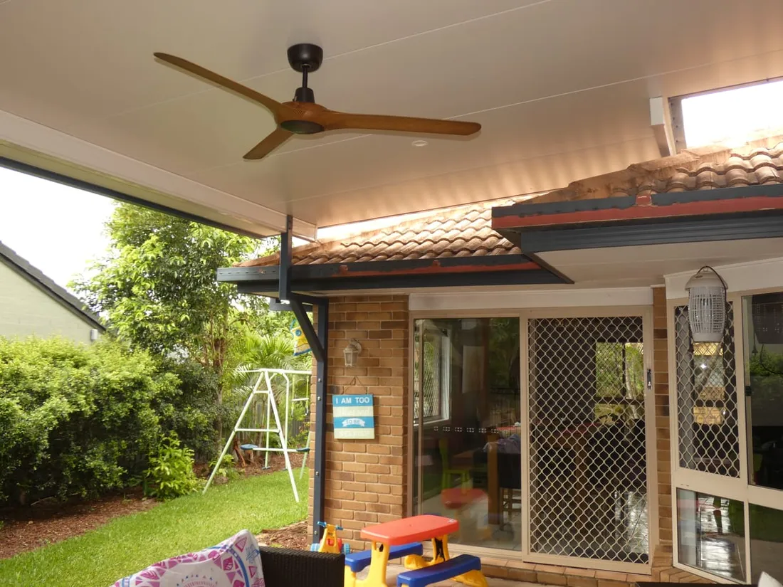 Insulated patio roof with ceiling fan over a brick home's entertaining area