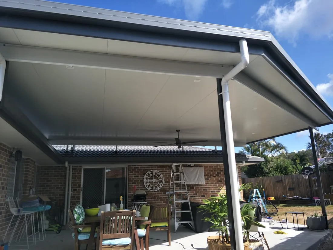 Wide insulated patio shading a brick home's outdoor dining area