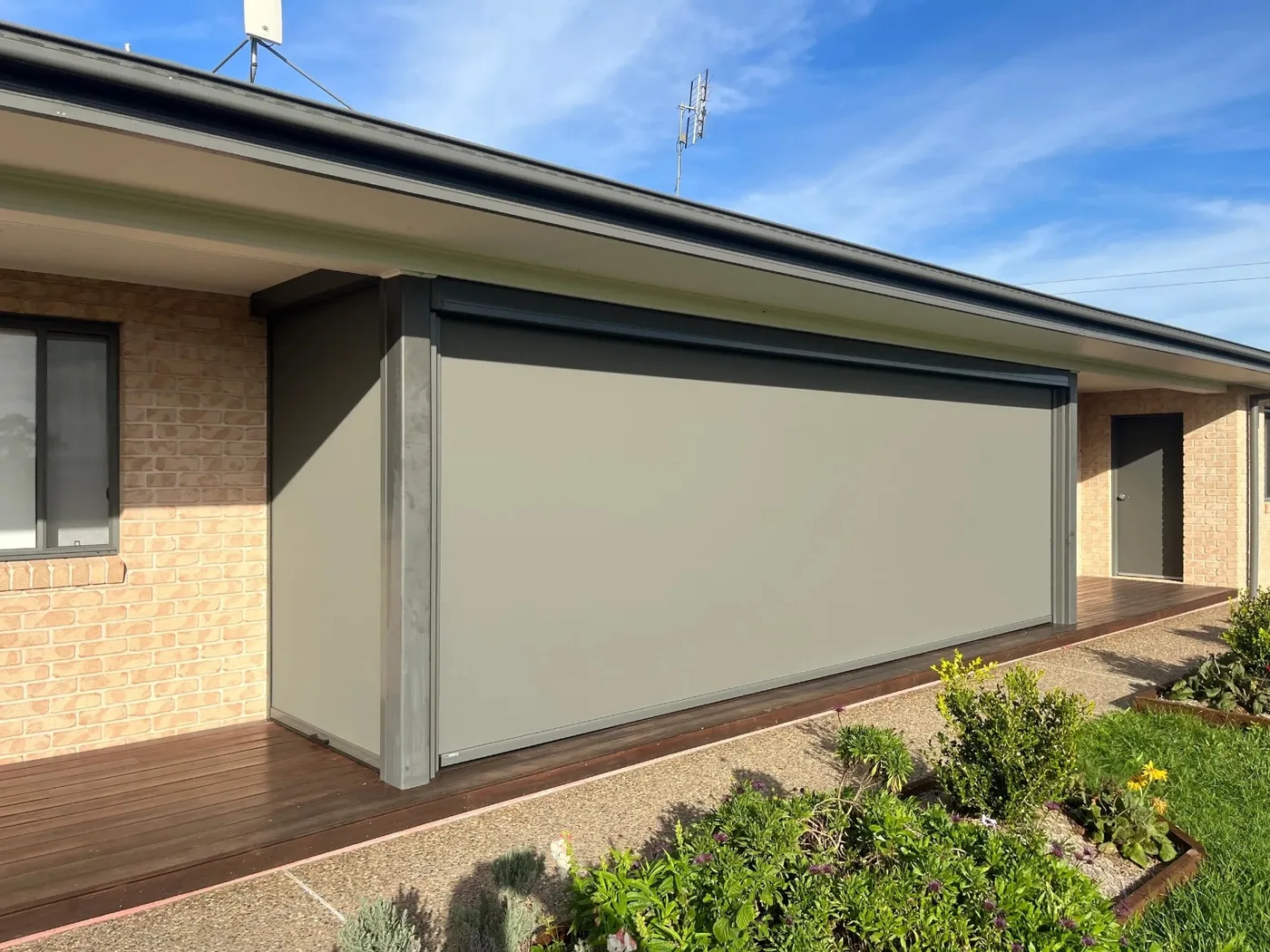 Outdoor blind shading a brick home's covered walkway, Dam Good Patios