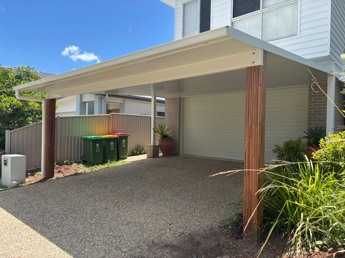 Skillion carport over a gravel driveway beside a two-storey home